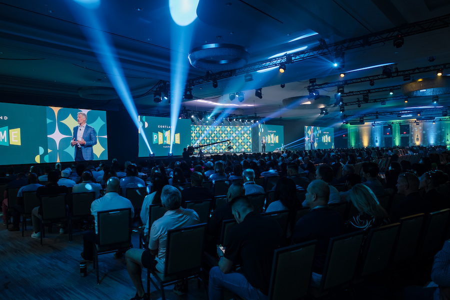 large LED video walls at an event, colorful lighting and spotlights show above a crowd