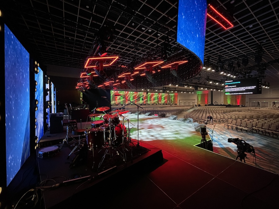 large event stage with drumset and colorful lights overlooking conference room seating area