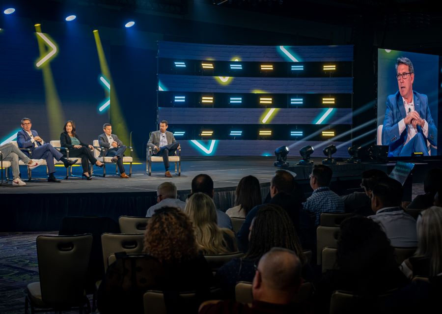 Panelists seated on a stage with dynamic lighting effects during the Cortland Primes 2022 event, showcasing professional stage and lighting design.