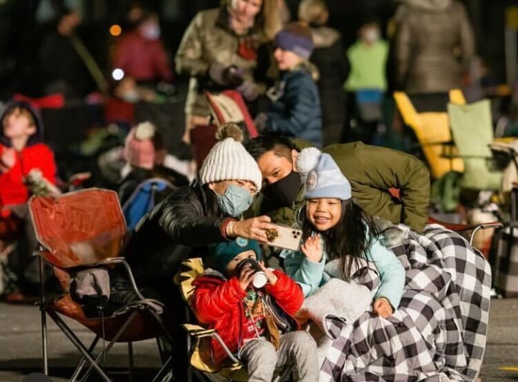 family taking selfies in an outdoor holiday event crowd.