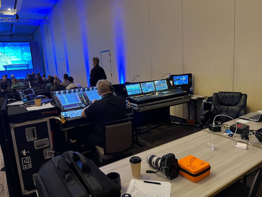 A Technical Elements employee sits at the AV mixing board during a corporate seminar event, ensuring a streamlined AV operation.