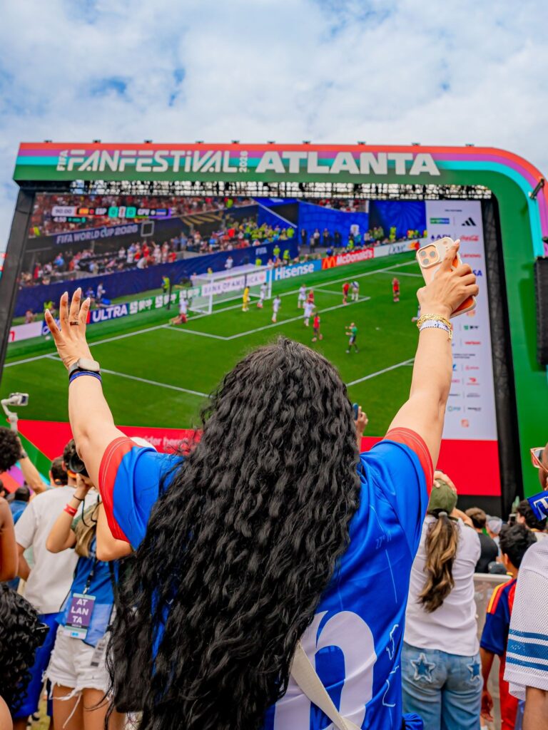 Woman with hands raised watching soccer game at the FIFA Fan Festival