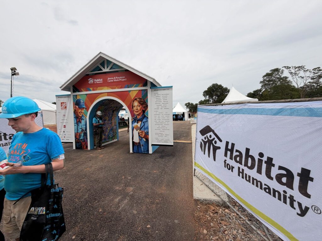 Outside of 40th Carter Work Project with Habitat for Humanity sign and people in hard hats